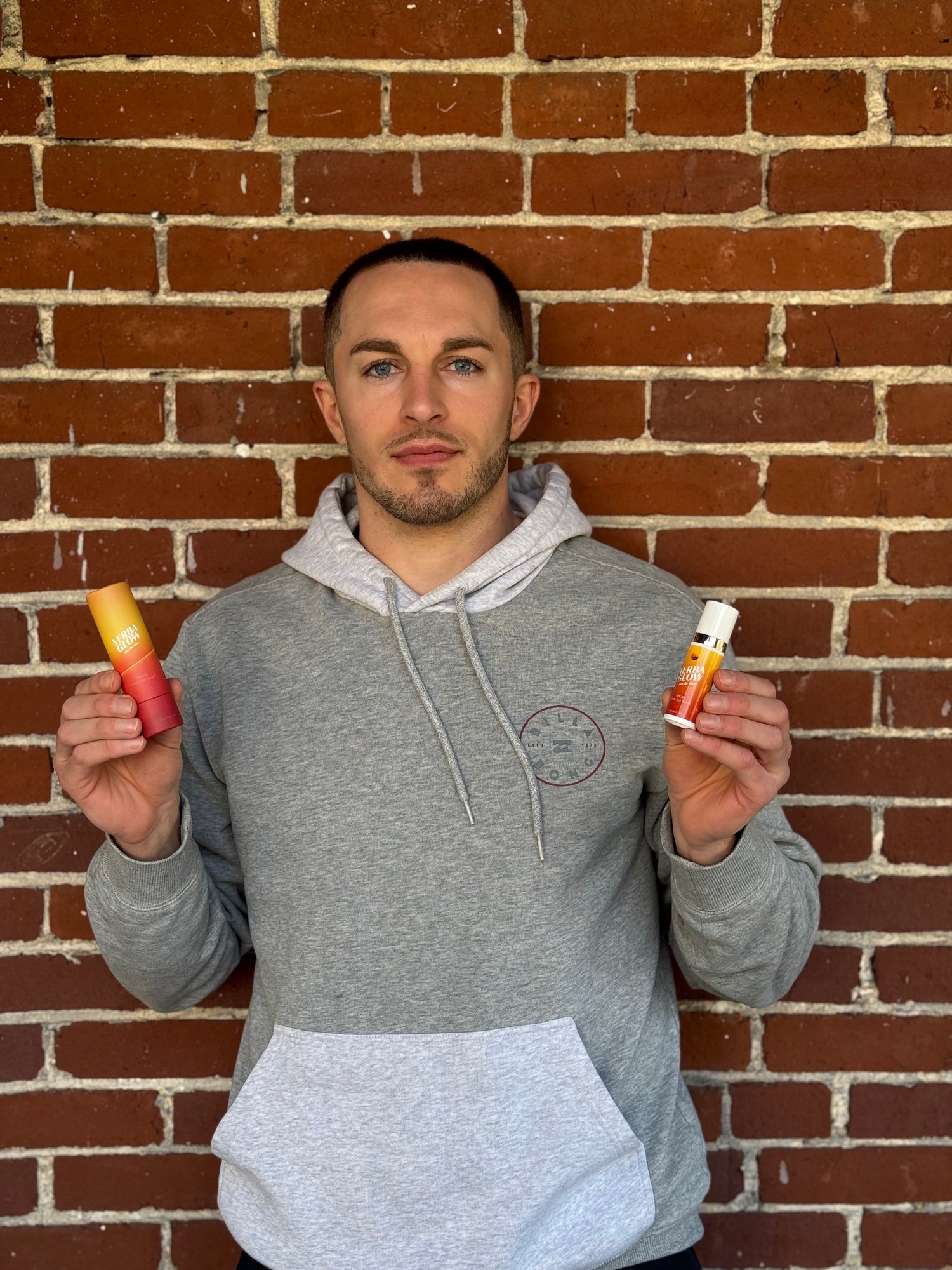 Yerba Glow founder Arum Krause holding the product against a brick wall backdrop