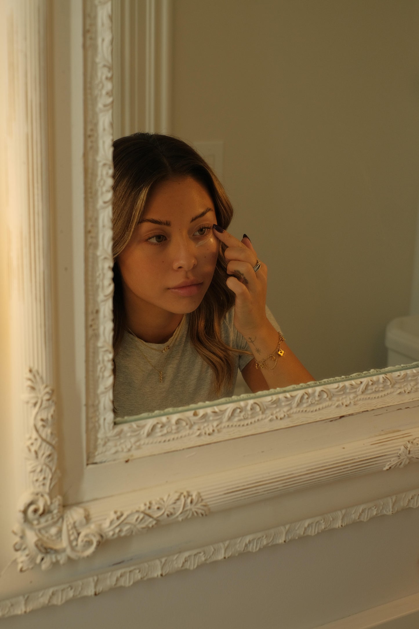 Woman applying Yerba Glow in front of a decorative mirror.